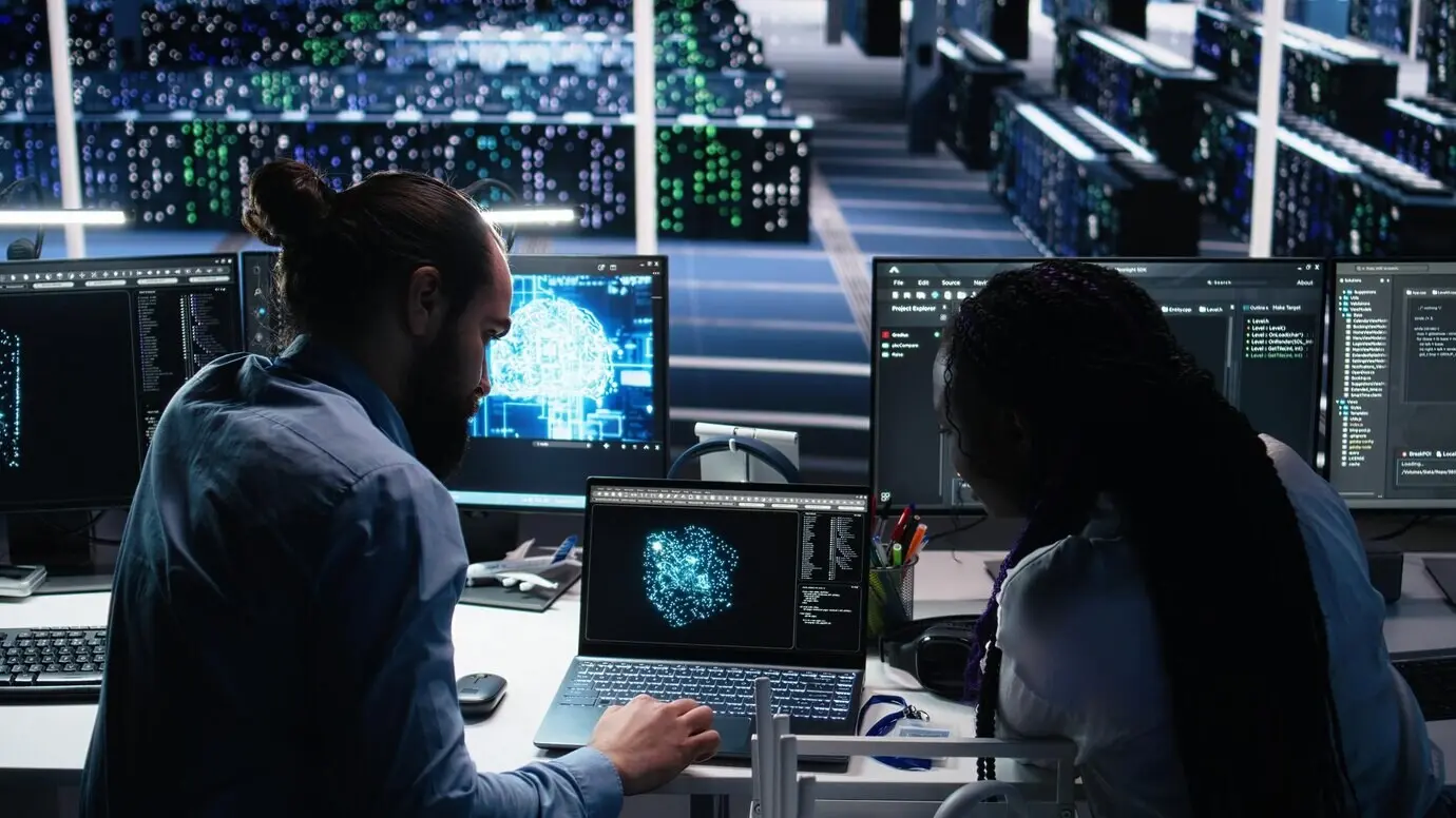 Администратор дата-центра обучает стажёра мониторингу нейронной сети с помощью ИИ.