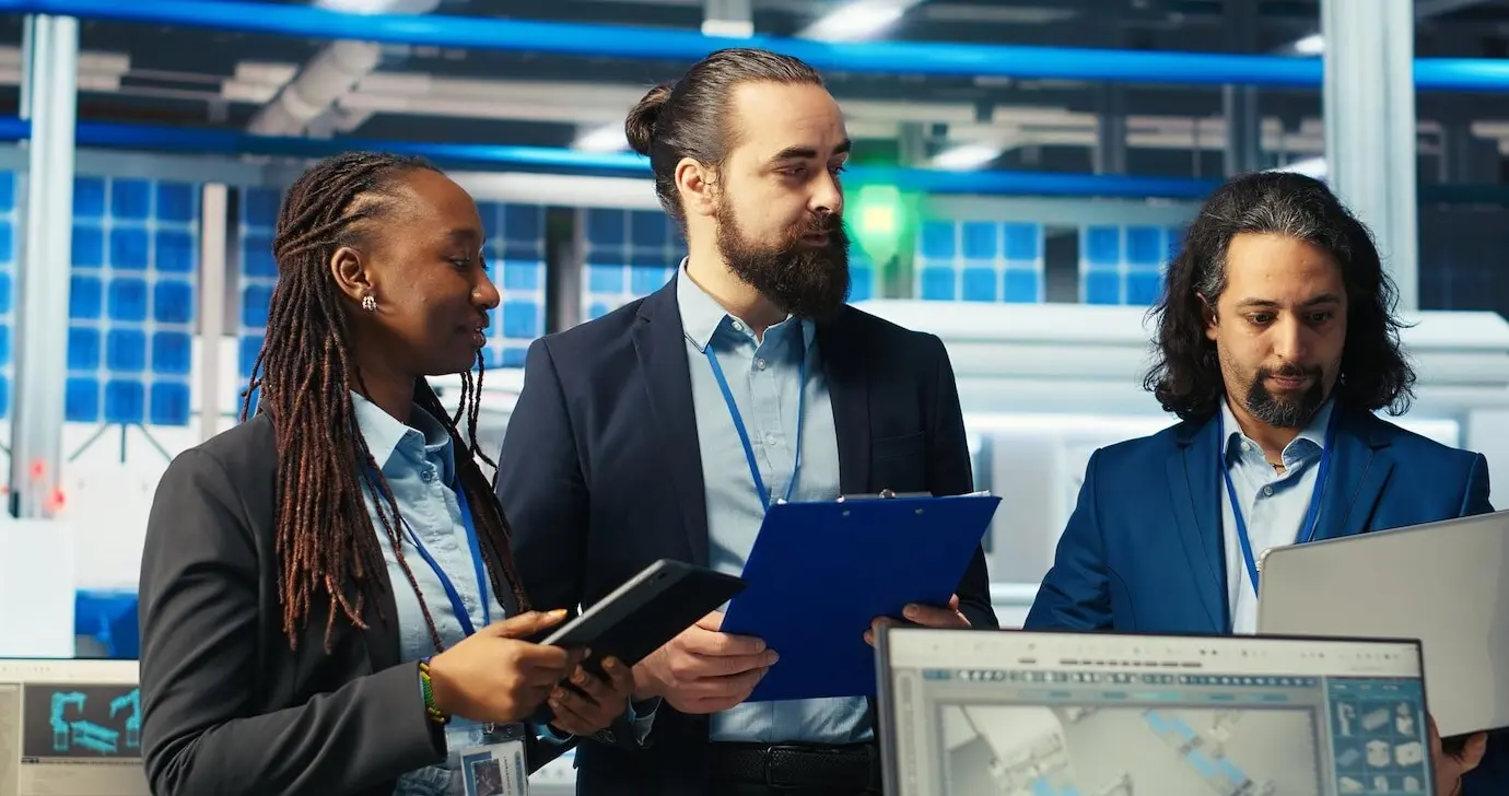 Команда счастливых супервайзеров, инспектирующих завод по производству солнечных панелей.